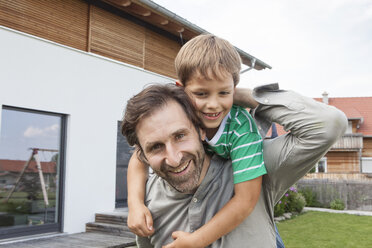 Portrait of happy father carrying son in garden - RBF003493