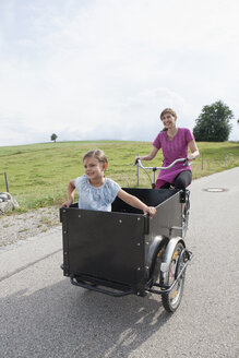 Mutter fährt Fahrrad mit Tochter im Anhänger - RBF003439