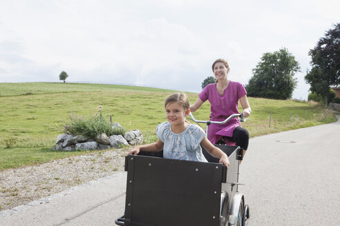 Mutter fährt Fahrrad mit Tochter im Anhänger - RBF003440