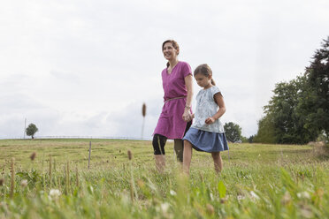 Mutter geht mit Tochter auf einem ländlichen Feld spazieren - RBF003442