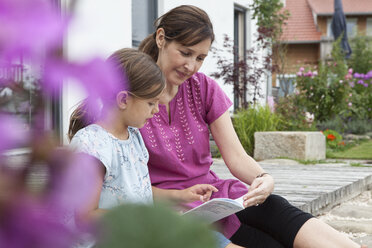 Mutter und Tochter lesen auf der Terrasse ein Buch - RBF003445