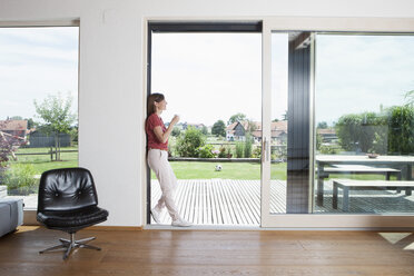 Mature couple leaning in garden door with cup of coffee - RBF003349