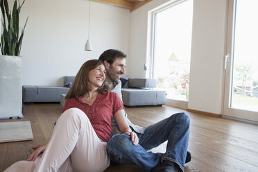 Mature couple sitting on floor, smiling happily - RBF003287
