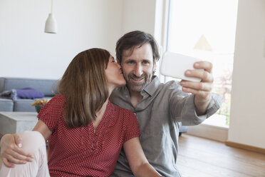 Älteres Paar sitzt auf dem Boden und macht ein Selfie mit einem Smartphone - RBF003353