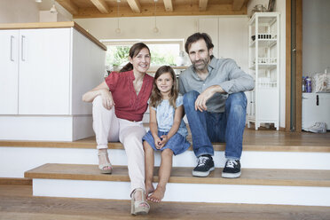 Happy family sitting on kitchen steps - RBF003362