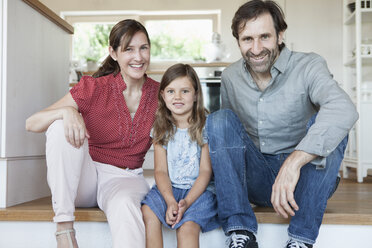 Happy family sitting on kitchen steps - RBF003363