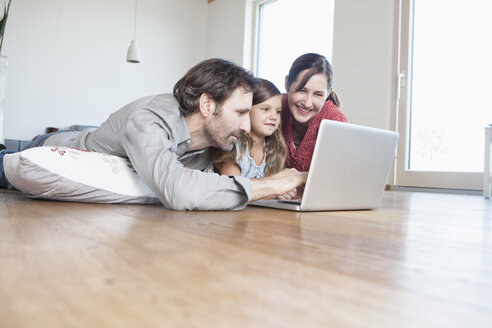 Glückliche Familie auf dem Boden liegend, mit Laptop - RBF003315