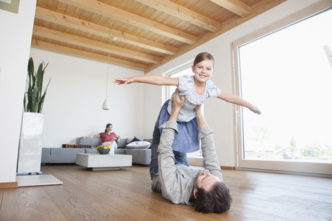 Father and daughter playing at home, pretending to fly stock photo