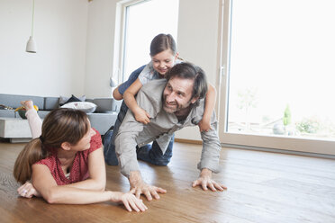 Glückliche Familie liegt auf dem Boden und spielt mit ihrer Tochter - RBF003318