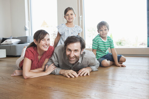 Glückliche Familie auf dem Boden liegend, lächelnd - RBF003323