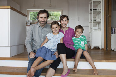 Happy family sitting on kitchen steps - RBF003325