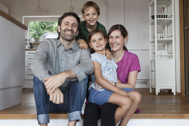 Happy family sitting on kitchen steps - RBF003365