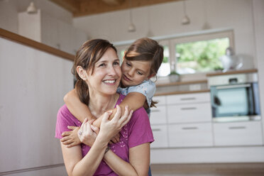 Mother and daughter sitting smiling in kitchen - RBF003337