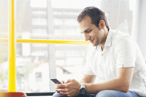 Man sitting in public transport looking at his smartphone stock photo