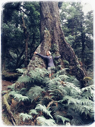 Neuseeland, Nordinsel, Te Urewera National Park, Regenwald, Eingeborenen Busch, Frau umarmt riesigen alten Baum - GWF004391