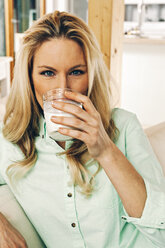 Blond woman drinking glass of milk - CHAF001087