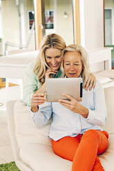 Happy mother and adult daughter using digital tablet at home - CHAF001090