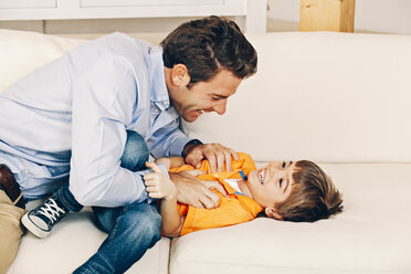 Playful father and son on sofa - CHAF001115