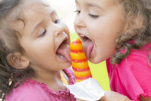 Two little sisters eating together a popsicle - ERLF000006