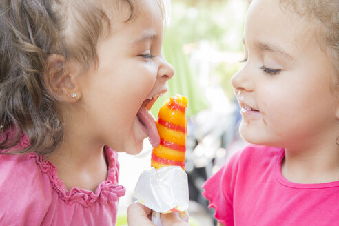 Zwei kleine Schwestern essen zusammen ein Eis am Stiel - ERLF000005