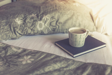 Book and cup of white coffee on a bed - ASCF000320