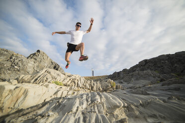 Spanien, Valdovino, junger Mann springt in felsiger Landschaft in die Luft - RAEF000307