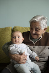 Porträt der Urgroßmutter, die mit ihrem Urenkel auf einer Couch sitzt - RAEF000309