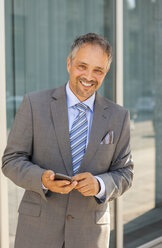 Porträt eines lächelnden Geschäftsmannes im grauen Anzug - JUNF000404