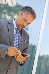 Portrait of businessman looking at his smartphone - JUNF000405