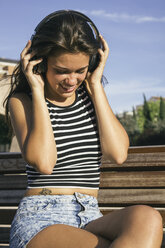 Smiling teenage girl hearing music with headphones - ABZF000099