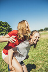 Carefree teenage girl carrying friend piggyback in park - AIF000045