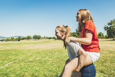 Carefree teenage girl carrying friend piggyback in park - AIF000046