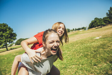 Carefree teenage girl carrying friend piggyback in park - AIF000048