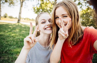 Two playful teenage girls making victory sign - AIF000052