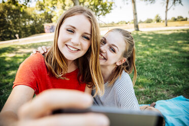 Zwei glückliche Teenager-Mädchen machen ein Selfie auf einer Wiese - AIF000056