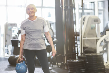 Ältere Frau im Fitnessstudio hält Kettlebell - MADF000514