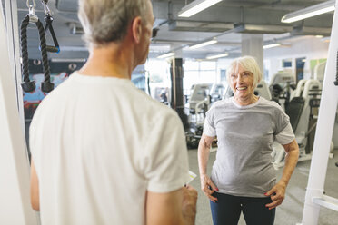 Ältere Frau lächelt Mann im Fitnessstudio an - MADF000521