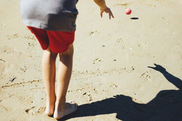 Rückenansicht eines Jungen, der am Sandstrand Boccia spielt - GEMF000319