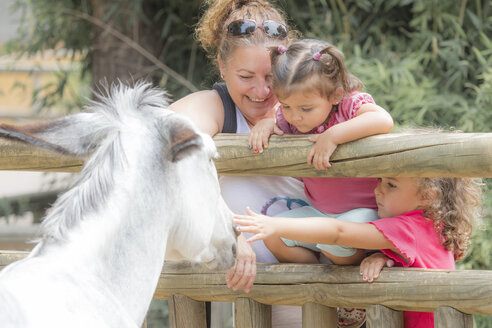 Frau mit zwei kleinen Mädchen beobachtet einen Esel - ERLF000012