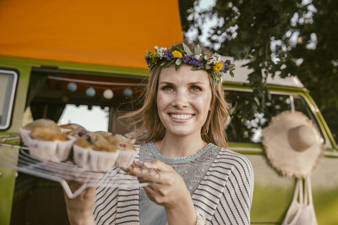 Hippie-Frau präsentiert vegane Muffins vor einem Lieferwagen - MFF002019