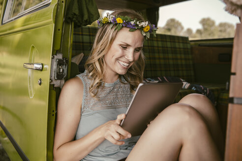 Happy young woman looking at tablet computer in van - MFF002026