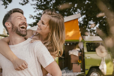 Playful couple in front of van in the nature - MFF002031