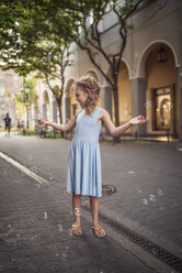 Germany, Berlin, Girl playing with soap bubble in the street - OPF000064