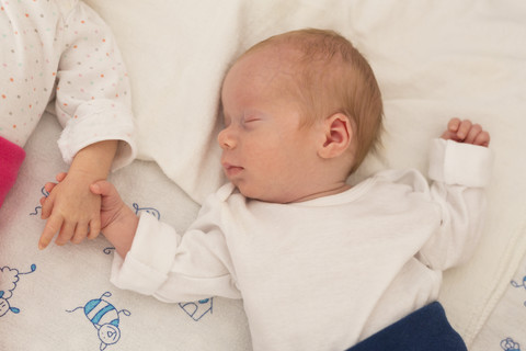 Neugeborene Zwillinge schlafen Hand in Hand, lizenzfreies Stockfoto
