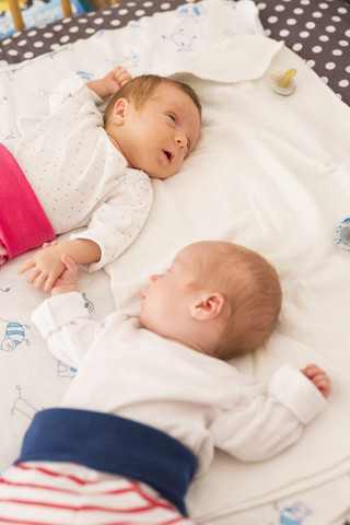 Neugeborene Zwillinge schlafen Hand in Hand, lizenzfreies Stockfoto