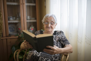 Ältere Frau liest zu Hause ein Buch - RAEF000315