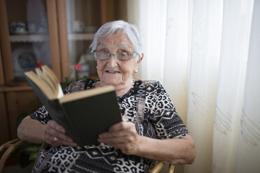 Ältere Frau liest zu Hause ein Buch - RAEF000318