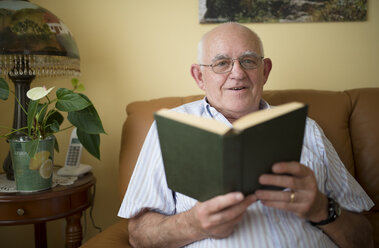 Porträt eines älteren Mannes mit Buch zu Hause - RAEF000319