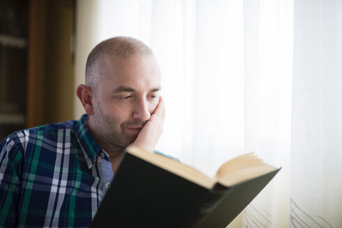 Porträt eines Mannes, der zu Hause ein Buch liest - RAEF000326