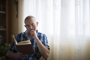 Porträt eines Mannes, der zu Hause ein Buch liest - RAEF000328
